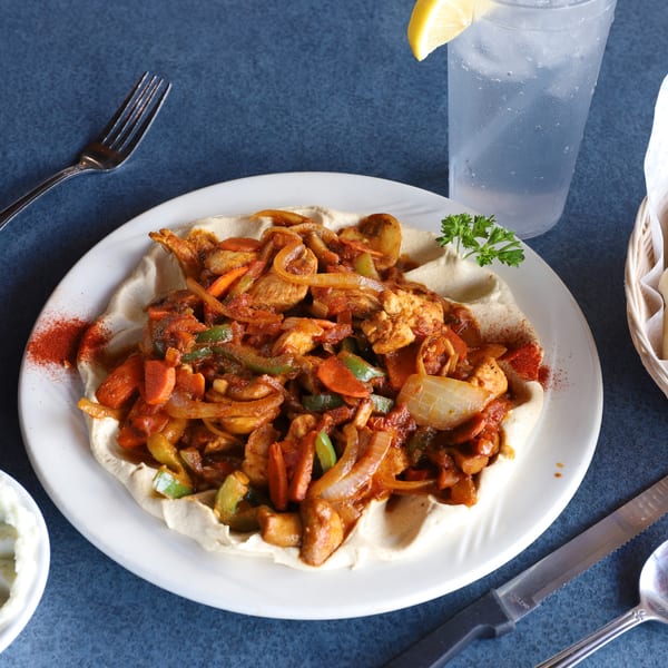 Le Kabob's chicken shawarma with vegetables and hummus, served with water and pita bread.