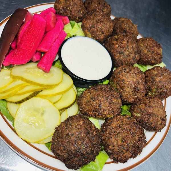 Le Kabob's falafel platter with pickled turnips, cucumbers, and a side of white sauce.