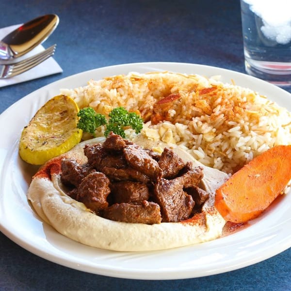Le Kabob's Mediterranean dish with beef, hummus, rice, lemon, and a carrot slice.