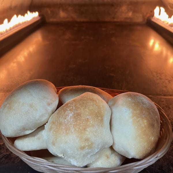 A basket of fresh pita bread sits in front of a fiery oven at Le Kabob.