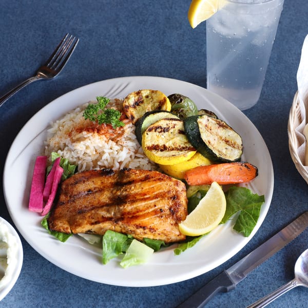 Le Kabob's grilled salmon with rice, grilled vegetables, pickled turnips, and a lemon wedge.